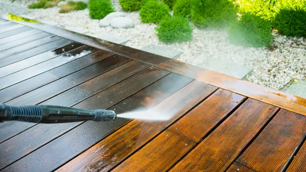 person pressure washing a wooden deck